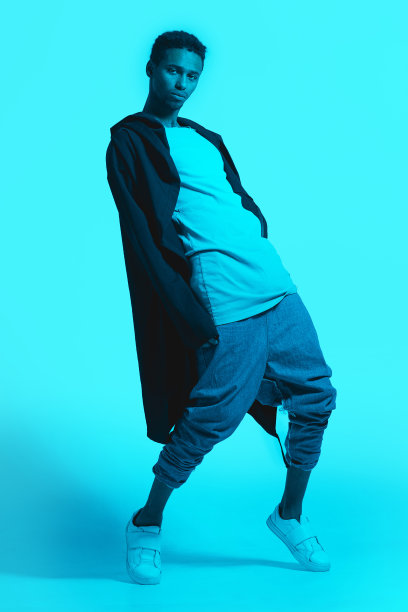 霓虹灯下的非裔美国黑人男性肖像。彩色背景，复制空间。严肃帅气的人穿着卫衣摆拍。舞者跳舞。洒的照片。图片下载