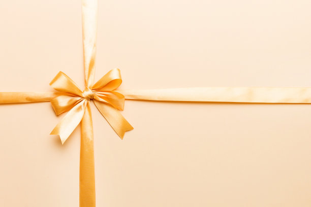 俯视图的金色丝带卷和黄蝴蝶结孤立在彩色背景。平面铺设与拷贝空间图片下载
