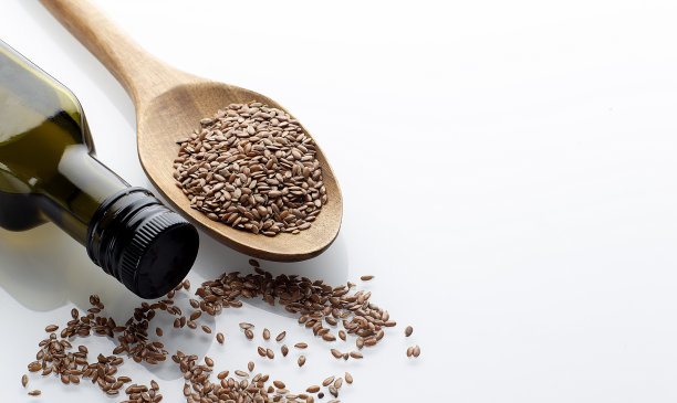 亚麻籽或亚麻籽放在勺子和碗里，在白色的背景上放上一杯亚麻籽油。亚麻籽或亚麻籽的概念。本空间图片下载