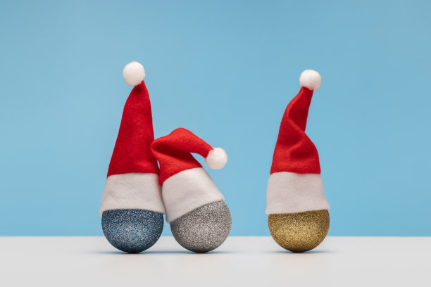 节日快乐。闪亮的气球戴着红色的节日帽。素材图片