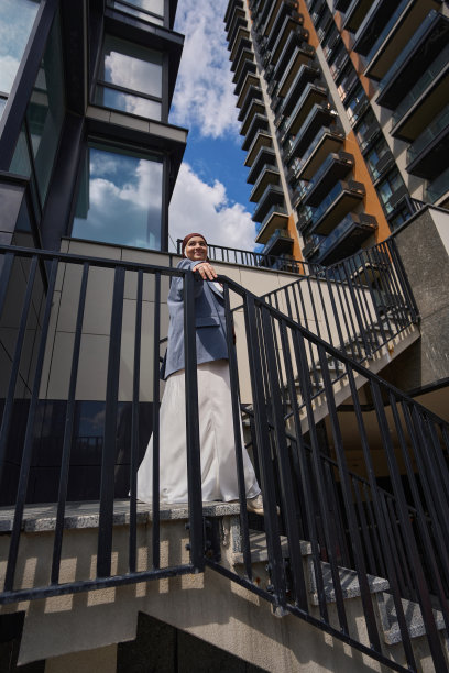 穆斯林妇女在高楼大厦的背景下走下楼梯图片下载