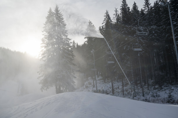 冬天山上的雪炮。喷着人造冰晶的雪枪。机器使雪。图片下载