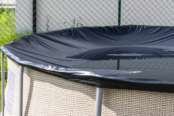 直径3.96米的大型扩展游泳池，黑色的盖子，设置在房子旁边的后院。图片下载