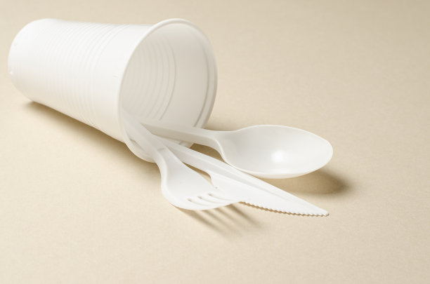 一次性白色塑料餐具，米色背景。自然污染的概念。副本的空间。图片下载