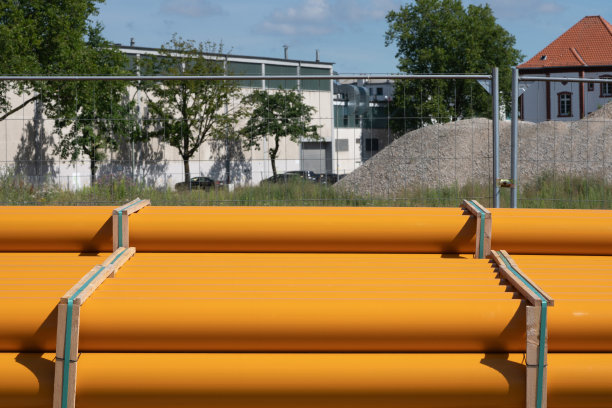 塑料橙色管道躺在金属格子篱笆。图片下载