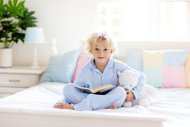 孩子在床上看书。孩子们在卧室里读书。图片下载