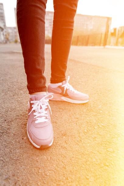 穿着牛仔裤和运动鞋的女人站在人行道上图片下载