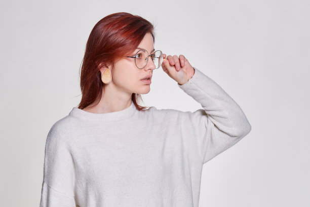 红发年轻女子手持眼镜近脸站在孤立的白色背景，拷贝空间。教学理念或制作公告广告图片下载