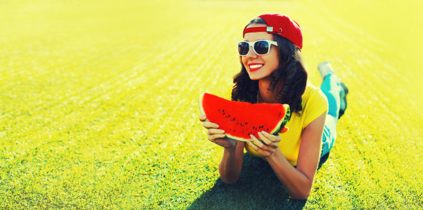 夏天的肖像快乐微笑的年轻女子吃新鲜多汁的西瓜片在夏季公园的草地上图片下载