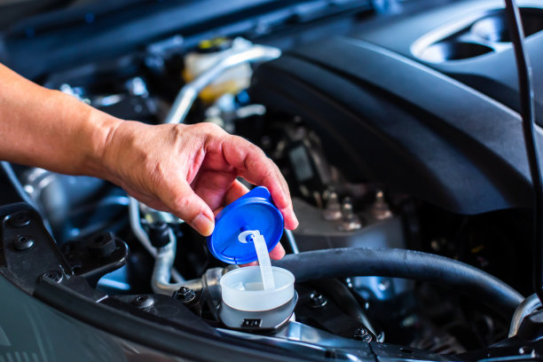 机修工将清水注入汽车发动机室的挡风玻璃或水箱内的雨刷。图片下载