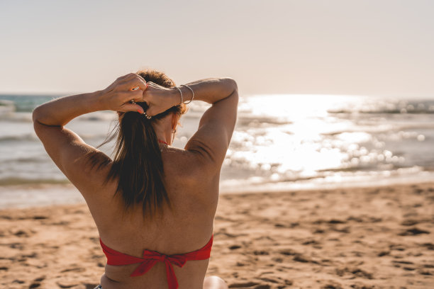 一个女人在沙滩上用橡皮筋挽着她的头发图片下载