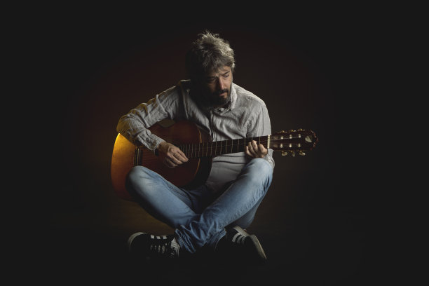 一名男子在黑色背景的工作室肖像中弹吉他图片下载