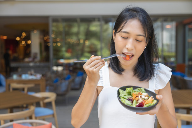 女人一边吃早餐一边玩智能手机。水果如西瓜、木瓜、甜瓜、百香果、橙汁和咖啡。放在灰色的餐垫上图片下载