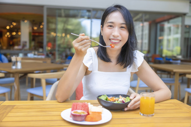 女人吃早餐。水果如西瓜、木瓜、甜瓜、百香果、橙汁和咖啡。放在灰色的餐垫上图片下载