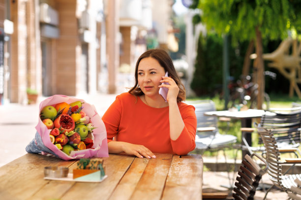 美丽的商业女性在红裙工作和赞赏礼物可食用的花束图片下载