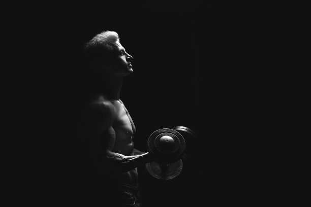 英俊的力量运动员在戏剧性的光。强壮的健美运动员拥有完美的肩膀，二头肌，三头肌，背部，三角肌和胸部。力量和动力图片下载