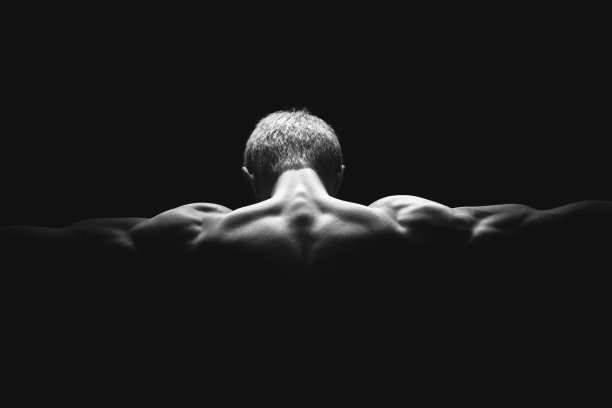 英俊的力量运动员在戏剧性的光。强壮的健美运动员拥有完美的肩膀，二头肌，三头肌，背部，三角肌和胸部。力量和动力图片下载