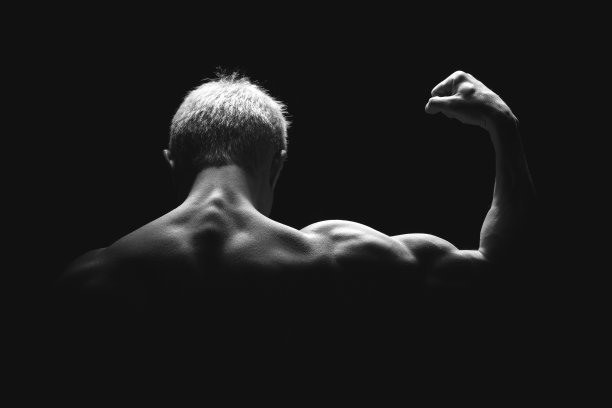 英俊的力量运动员在戏剧性的光。强壮的健美运动员拥有完美的肩膀，二头肌，三头肌，背部，三角肌和胸部。力量和动力图片下载