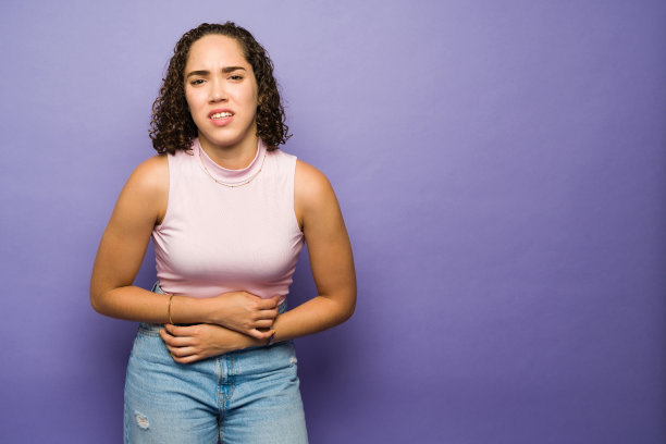 生病的妇女抱着她的胃，因为抽筋而感到疼痛图片下载