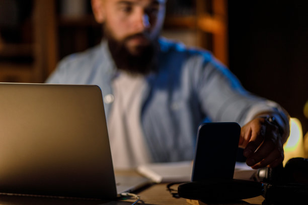 一个商人在接到电话时伸手去拿他的智能手机图片下载