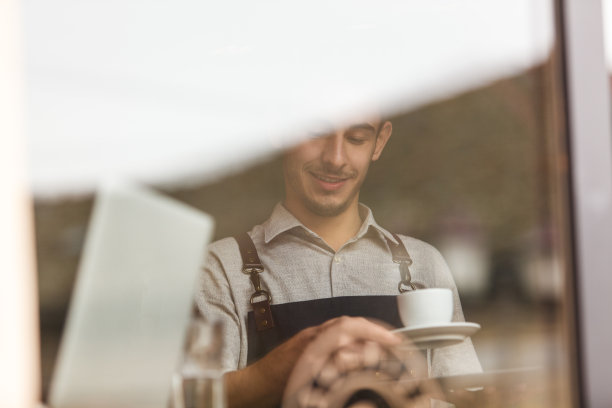 微笑的服务员在咖啡店提供或清洗一杯咖啡图片下载