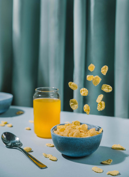 早餐玉米片、飞溅的食物、餐桌上的玉米片和橙汁静物图片下载