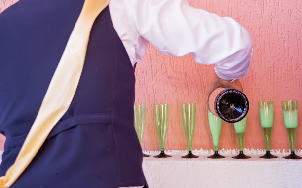 侍者倒了香槟。一个男人往玻璃杯里倒香槟。图片下载