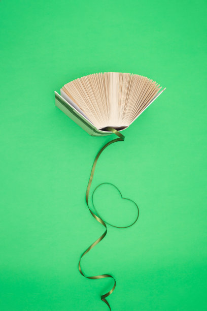 旧书和绿丝带在明亮的绿色背景。教育、知识或自然观念。平的。图书爱好者。图片下载