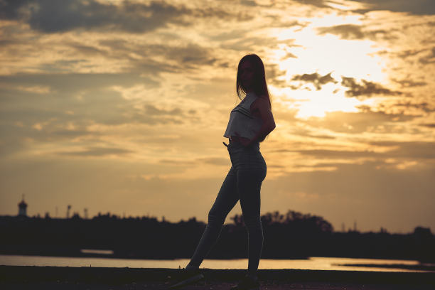 观看海上日落的年轻女子剪影。惊人的自然背景。色调照片与复制空间。图片下载