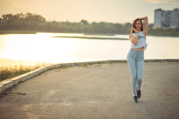 年轻美丽的白人金发女孩听音乐与智能手机在城市散步和舞蹈与耳机微笑-放松，青春，解放的概念图片下载