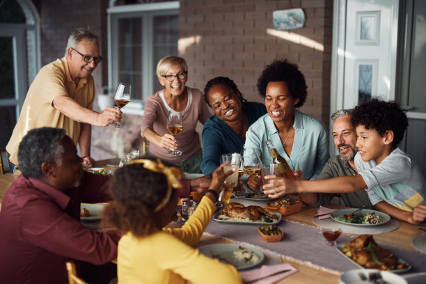 快乐的多种族大家庭举杯庆祝，一起在露台上用餐。图片下载