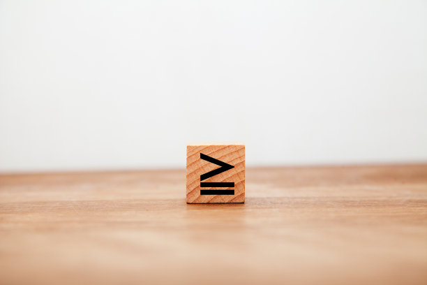 ≧象征。更大的平等。不等号。相同或更大。写在木块上的。图片下载