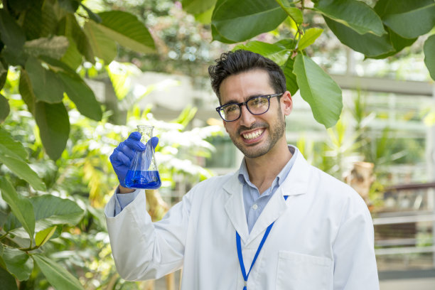 生物学家在温室里展示一个装有液体的实验室烧瓶图片下载