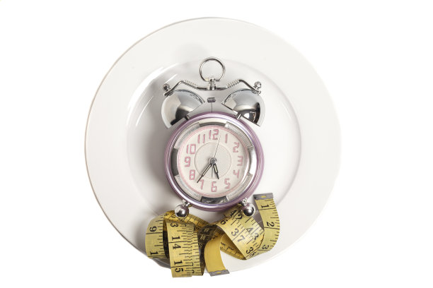 饮食的概念。带有卷尺的闹钟，在一个白色背景上隔离的板上图片下载