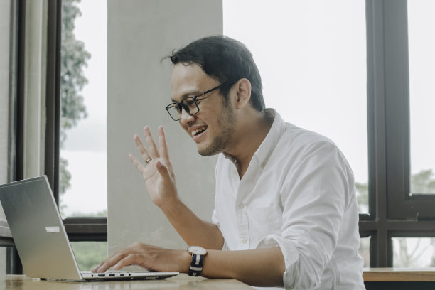 年轻的亚洲男子坐在咖啡馆里用笔记本电脑开视频会议图片下载