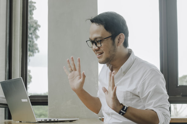 年轻的亚洲男子坐在咖啡馆里用笔记本电脑开视频会议图片下载