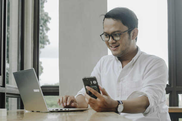 年轻的亚洲商人在咖啡馆的办公桌前用智能手机聊天图片下载