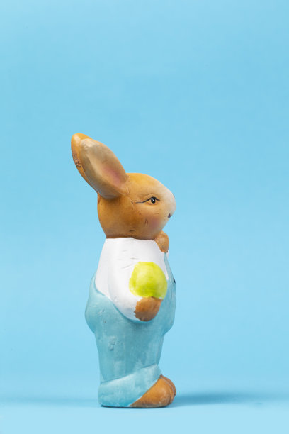 一个泰迪复活节兔子和一个鸡蛋在蓝色的背景。复活节卡片。图片下载