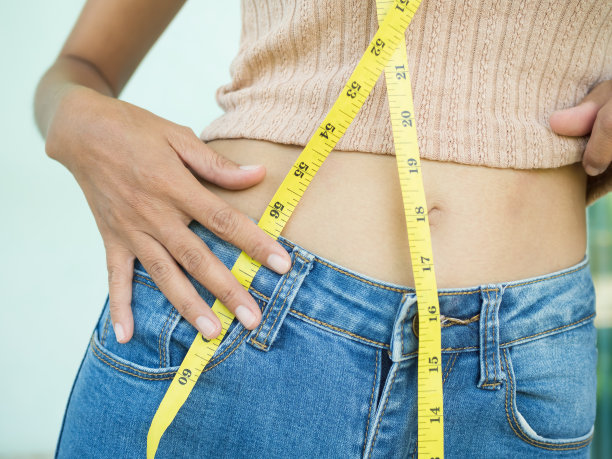 腰女人与牛仔裤卷尺。身材苗条身材匀称的年轻女孩。图片下载