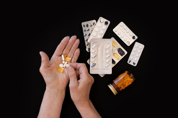 在一个黑色的背景，大量的各种药丸和一个手特写图片下载