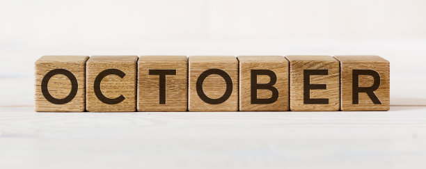 “十月”这个字印在木块上。它们躺在以夏季花园为背景的其他立方体上。图片下载