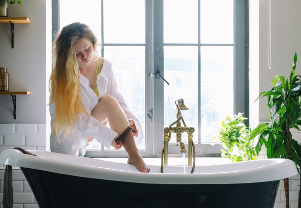 一个穿白衬衫的女人在浴室里脱下她的袜子图片下载