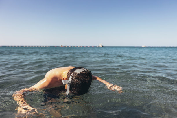 阳光明媚的日子里，男孩在海里跳着，戏水。图片下载