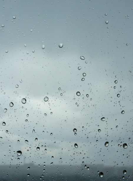 水滴在玻璃上。透明的窗户上有雨滴或气泡。纯净水洒在蓝色的背景上。许多大小和形式。垂直照片背景。图片下载