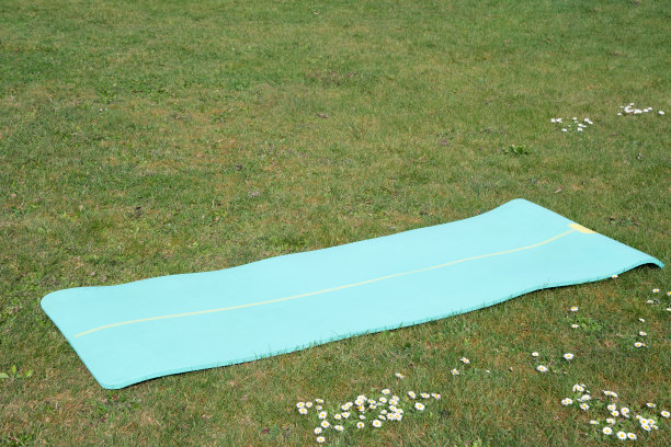 绿色瑜伽垫躺在户外锻炼瑜伽，夏天的时间图片下载