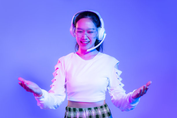 年轻的亚洲女性穿着白衬衫，戴着眼镜和耳机，在渐变的蓝色和紫色背景上摆姿势。图片下载