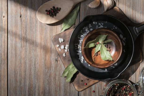 用盐、大蒜、香料、月桂叶和胡椒制作的铸铁平底锅放在质朴的阁楼木桌上。厨房食物背景，有菜单或食谱俯视图的复制空间图片下载