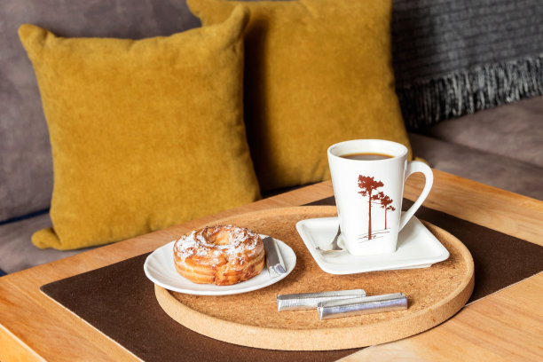 在客厅的咖啡桌上，一杯早餐咖啡和一块蛋糕。图片下载