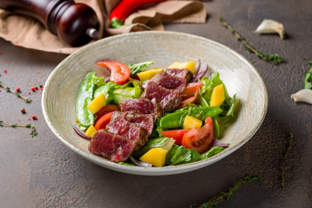 牛排沙拉配牛肉和蔬菜放在棕色的桌子上图片下载