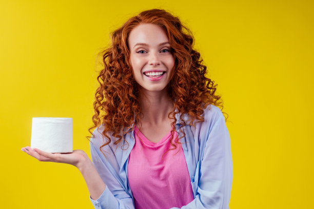 红发卷发姜女与卫生生态纸在工作室黄色的背景图片下载